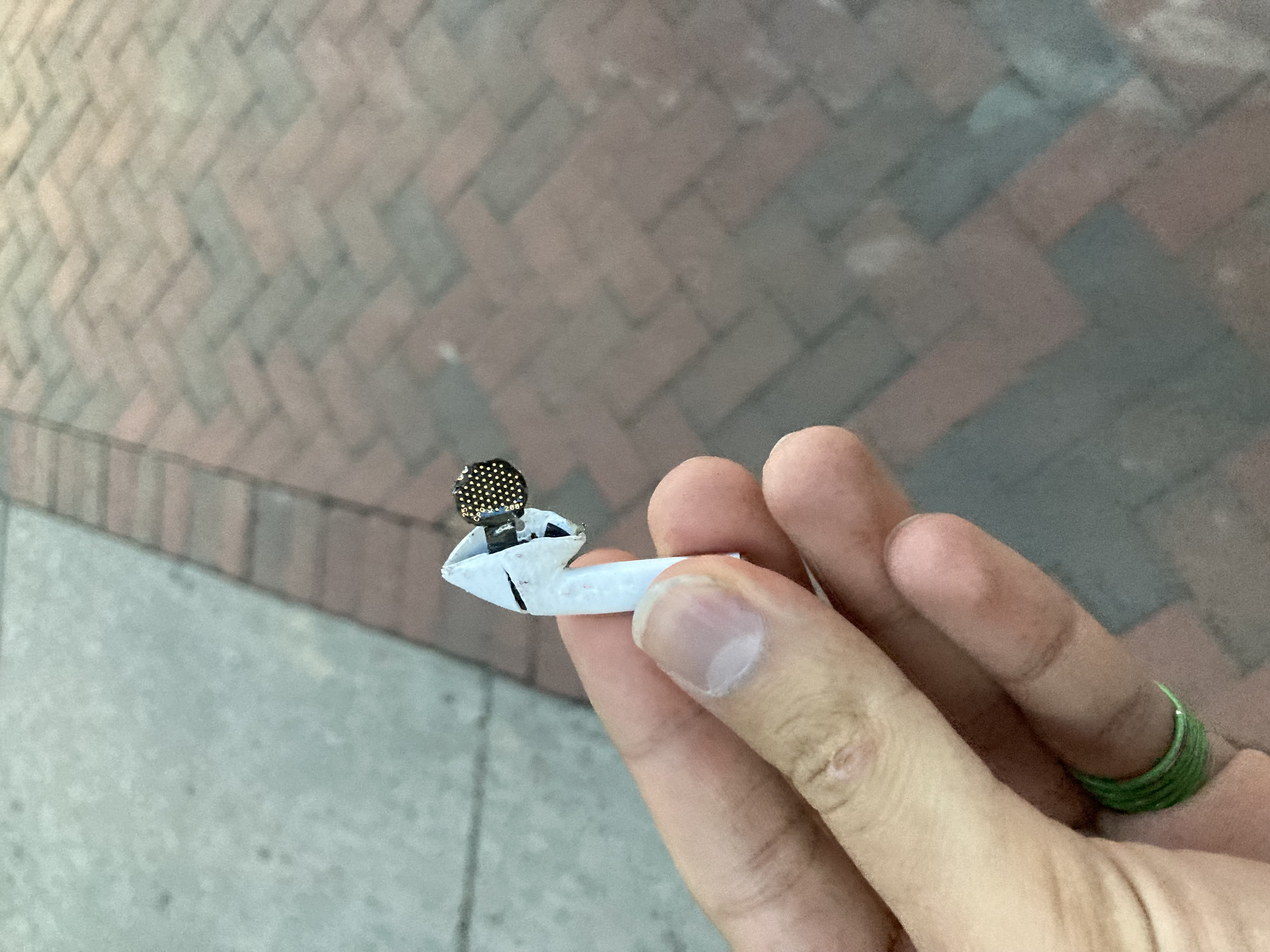a hand holding a destroyed left white airpod